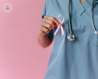 A breast doctor holding a ribbon. 