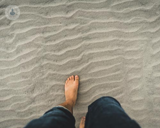 Someone walking on beach who is at risk of developing hallux valgus (bunion)