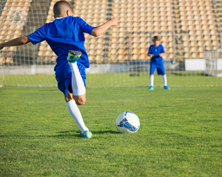 A boy playing football, about to score.