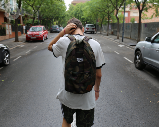 Teenage boy walking down the street touching the back of his head