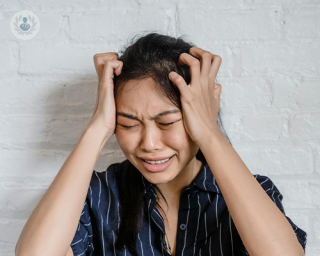 A woman holds her head with an expression of agony