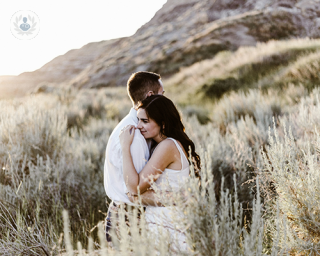 A man and a woman in a relationship hugging in a field of flowers