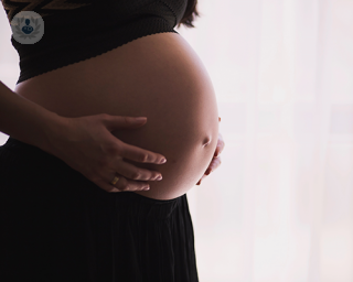 A pregnant woman hugging her belly.