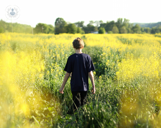 A boy walking through a field of flowers.