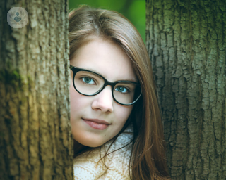 girl in glasses, head between to trees