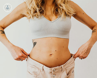 A woman demonstrates the change in her silhouette by donning a pair of jeans that no longer fit