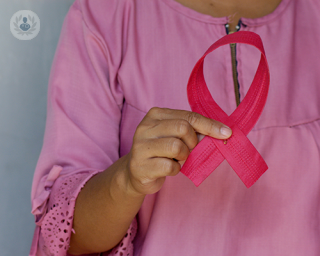 A woman holding a pink ribbon symbol of breast cancer