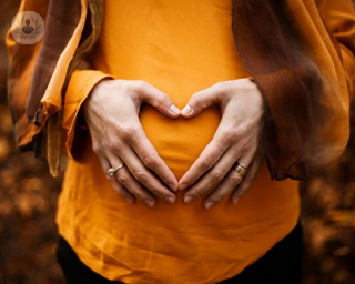 woman holding her baby bump in a heart shape