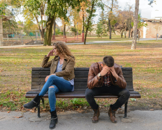Man and woman upset sat on a bench outside