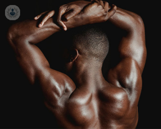 A man flexes, showing off the results of shoulder surgery