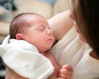 A sleeping baby held in their mother's arms