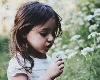 A little girl blowing on a dandelion
