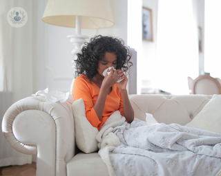 A woman blowing her nose with a tissue