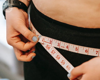 A woman using a measuring tape around her waist