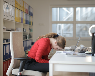 A teenager bent over her laptop, feeling frustrated.