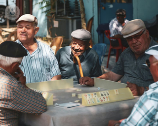 A group of older men sit around a table playing a game 