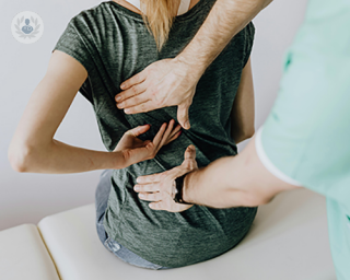 A woman with back pain, undergoing a physical examination