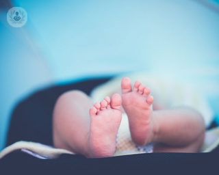 A baby in a nappy lies on the changing table, with its feet facing the camera. Children and infants are at risk from having urinary tract infections.