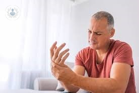 A man feeling pain in his wrist and looking worried. 