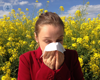 A girl with allergy blowing her nose in a field of flowers