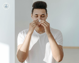 A young man pressing a tissue to his nose to stop a nosebleed