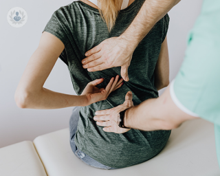 A young woman with back pain undergoing a clinical examination