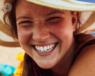 A young woman grins at the camera with white teeth