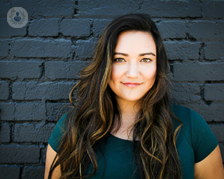 A young woman standing in front of a brick wall.