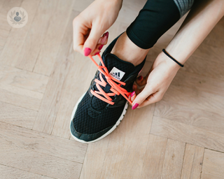 A young woman tying the shoelaces of her running shoes