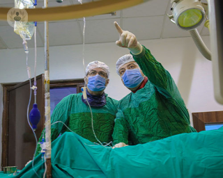 Doctors standing over a patient doing an interventional cardiology procedure