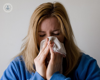 A woman blowing her nose with a tissue