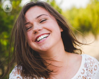 A young woman smiling, showing her full teeth