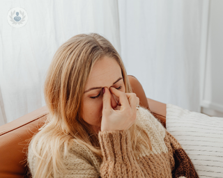 A young woman pinching the top of her nose, due to nasal congestion caused by sinusitis.