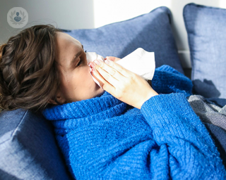 A young woman blowing her nose with a tissue