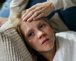 A young boy laying on the sofa, looking unwell