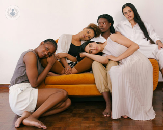 A group of femmes sit in a pile and stare somberly at the camera. Gynaecological cancer