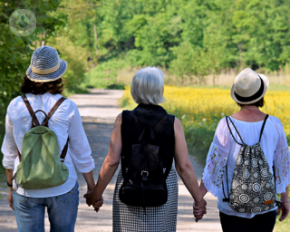 A group of three menopausal women on a walk through the countryside, holding hands. 