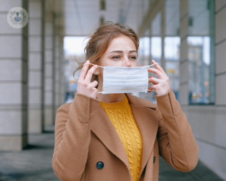 A woman carefully putting on a COVID-19 mask