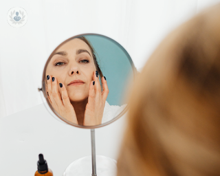 A woman looking at her face in front of a mirro