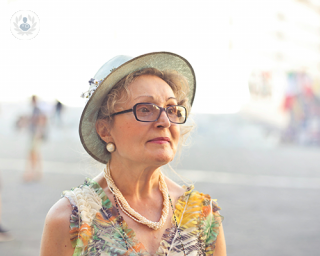 An elderly woman wearing a dress and a hat