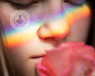 A young woman smells a flower, her sense of smell unimpaired by her less invasive rhinoplasty