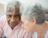 An elderly couple resting their temples against each other