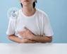 Young man sat at table with hands on his stomach