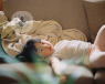 A toddler lies on their back on the sofa.