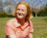 A woman sitting on grass at a park.