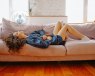 A women lying on a sofa due to PMS with her hands over her pelvic area.