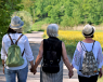 Three adult women holding hands while on a walk through the countryside.