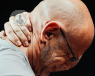 An elderly man holding the back of his neck in pain.