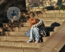 A young redhead girl sat on a staircase hiding her face between her legs