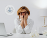 An adult woman in front of her computer, feeling overwhelmed and stressed.